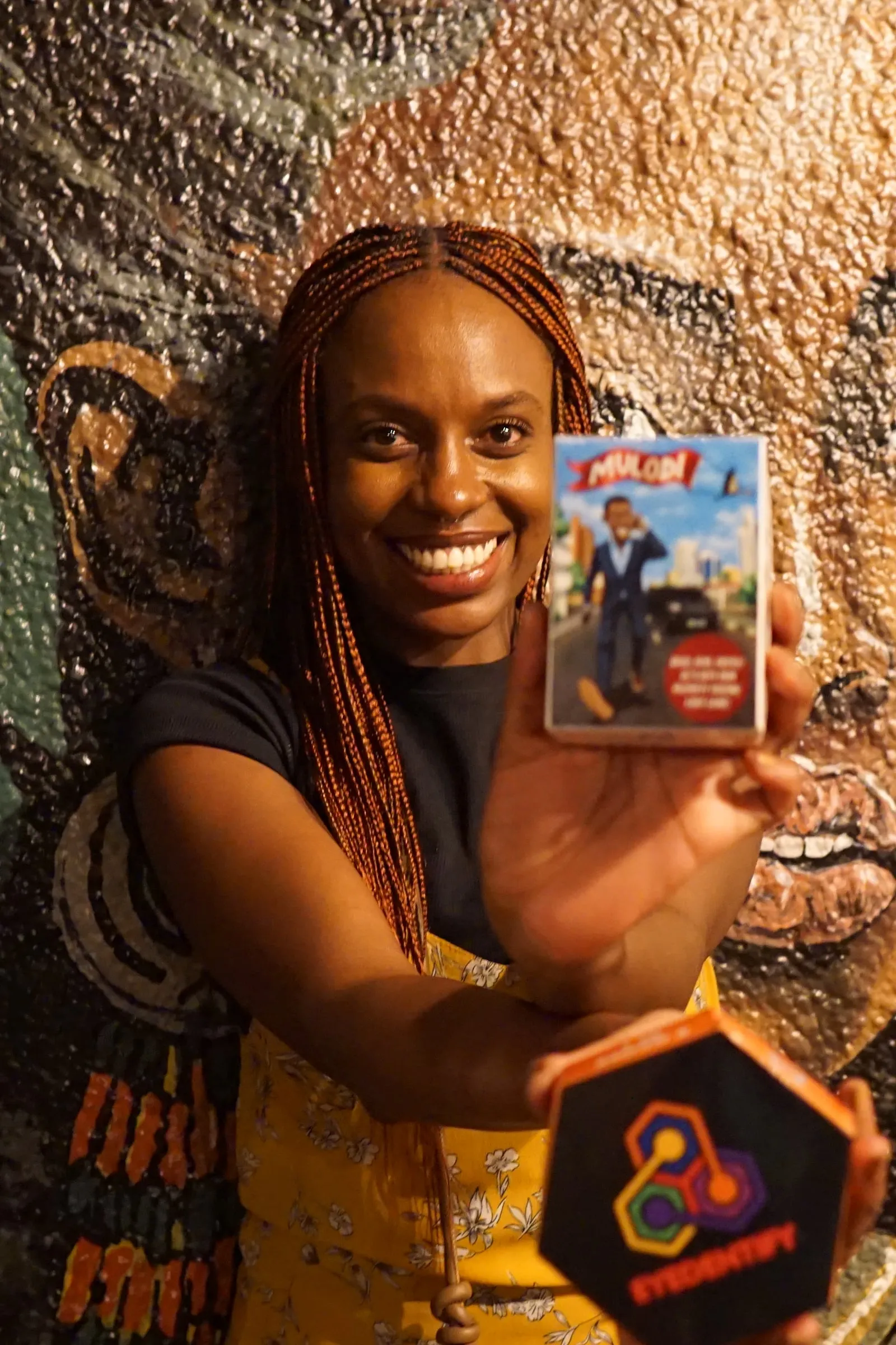 A fan holding Mulodi and Eyedentify in front of a mural