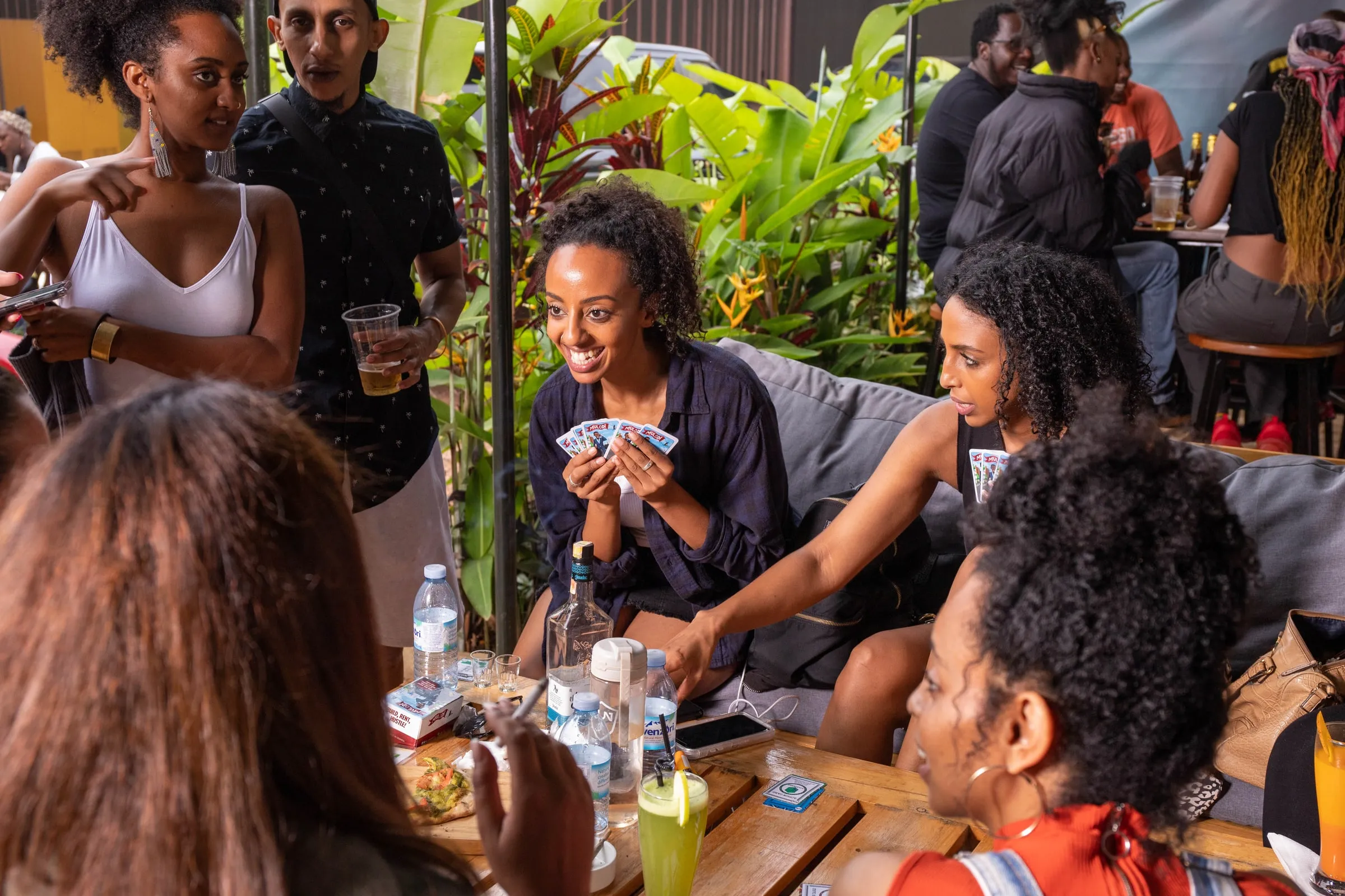 Friends laughing over a game of Mulodi at an outdoor café